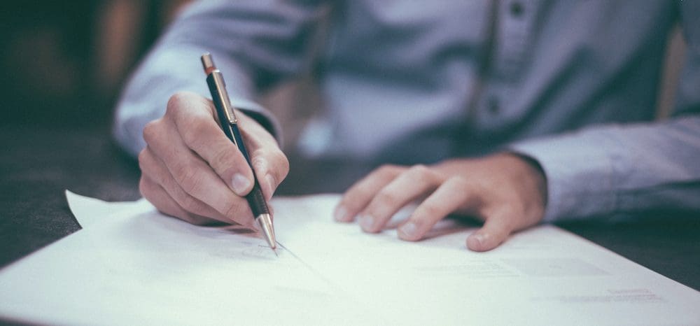 Man holding pencil, writing on paper. Are tax credits refundable? Runey & Associates Wealth Management. 